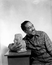 "Langston Hughes next to a small sculpture"