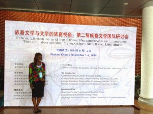 "Deaweh standing in front of a poster at the Wuhan Symposium"