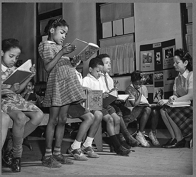 "A schoolgirl reading a book aloud during class"