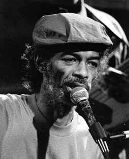 "Black and White image of Gil Scott-Heron singing into a mic"