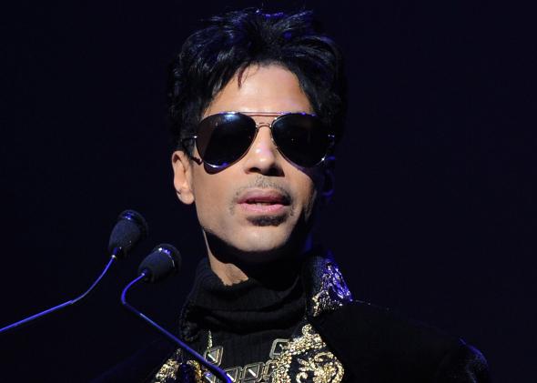 prince behind a microphone with black sunglasses on