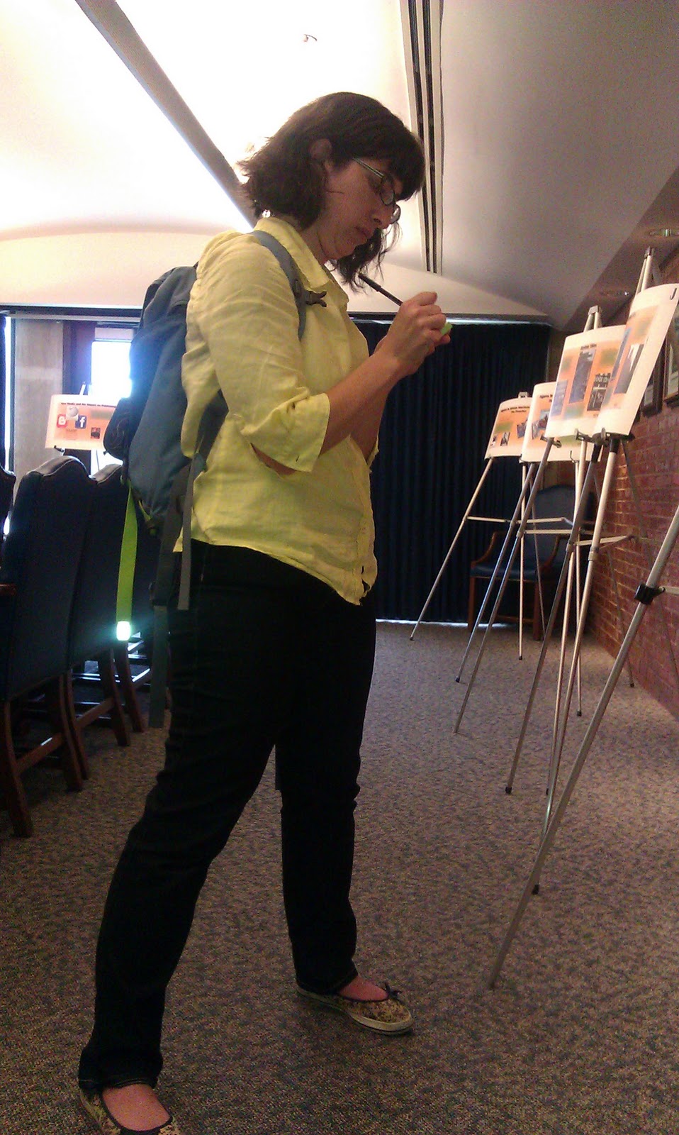 "A woman in a yellow shirt taking notes about the exhibition "