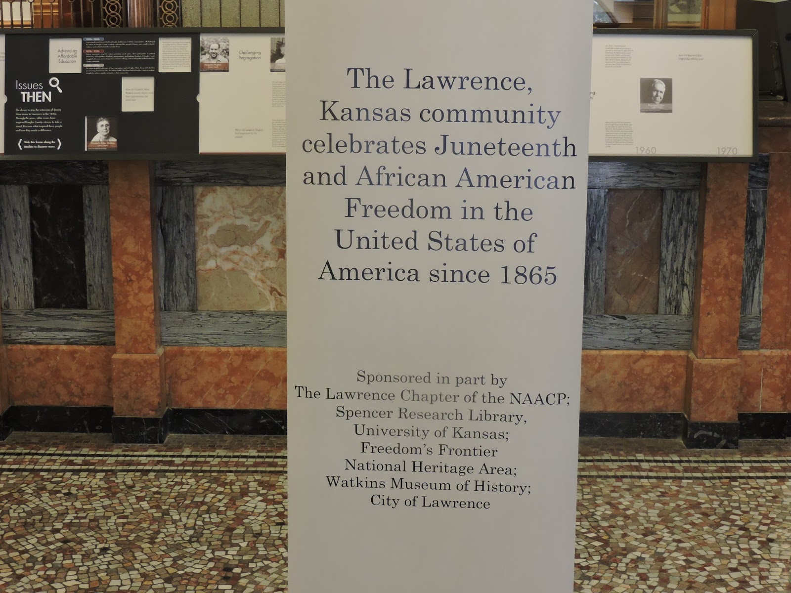 close up of one of the flag stands that says "The Lawrence, Kansas community celebrates Juneteenth and African American Freedom in the United States of America since 1865"