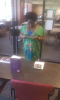 "A woman in a green top looking at the Black Literary Report on a table"