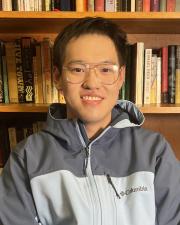 Brian Li sitting in front of a bookshelf.